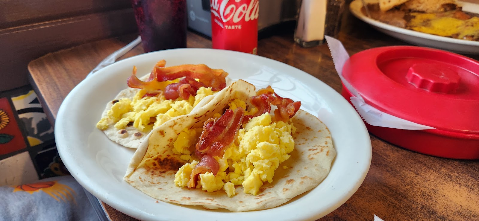 Bacon and egg breakfast tacos on a plate with a soft drink